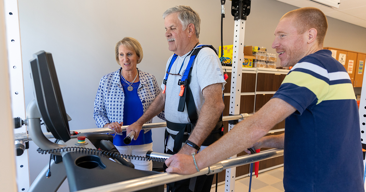A stroke survivor walks on an adapted treadmill as part of a high-intensity interval training clinical trial aimed at improving gait while Physical Therapy Department Chair Darcy Reisman and research associate Henry Wright monitor his progress. 