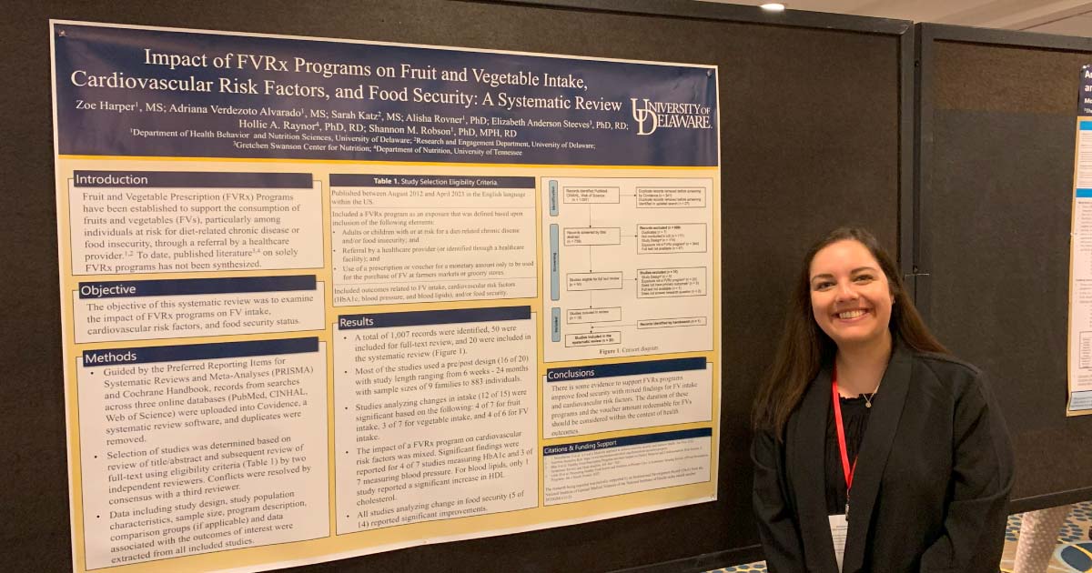 Woman standing in front of poster presenting her research on food programs