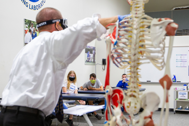 Instructor teaching a class using a model of a skeleton