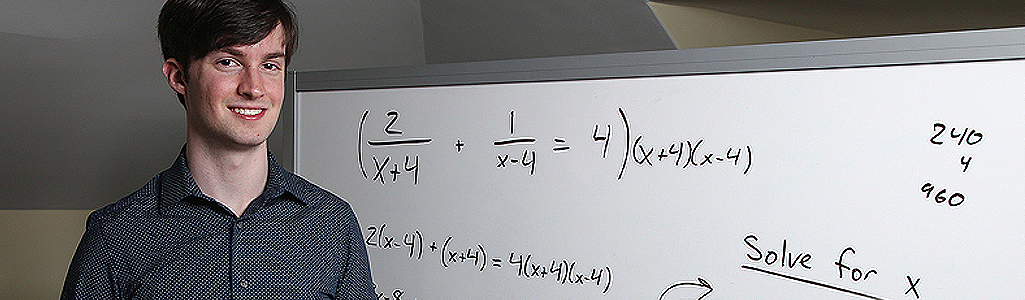 Mathematics graduate student in front of a white board with math problem.