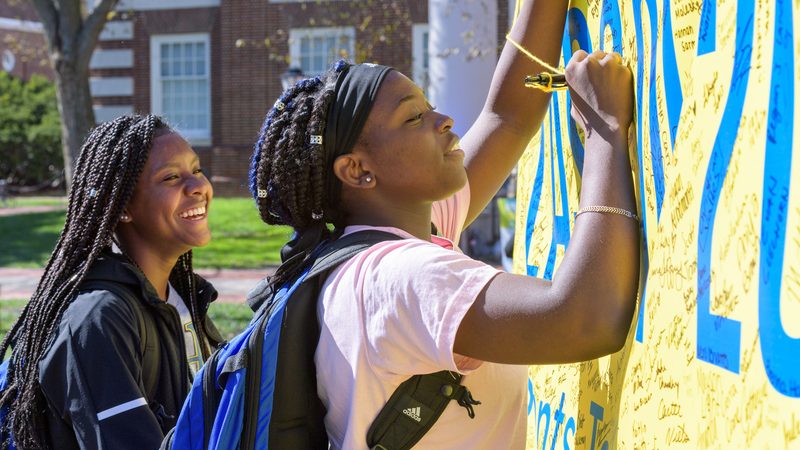 Students sign their class year banner at a spirit event hosted by the UDAA. 