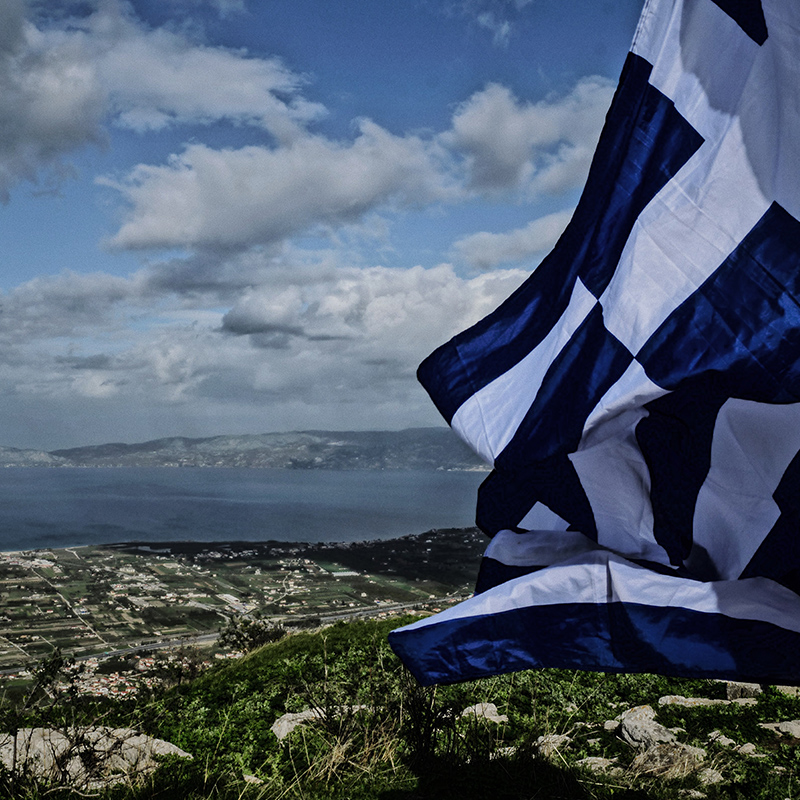 A view of Athens with a waving Greek flag.