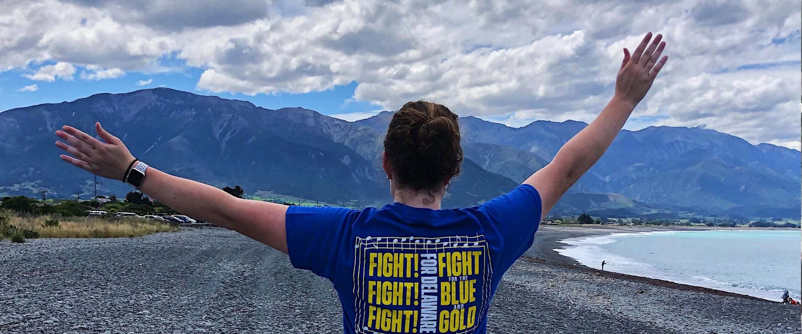 student spreading out hands and she looks at view in New Zealand