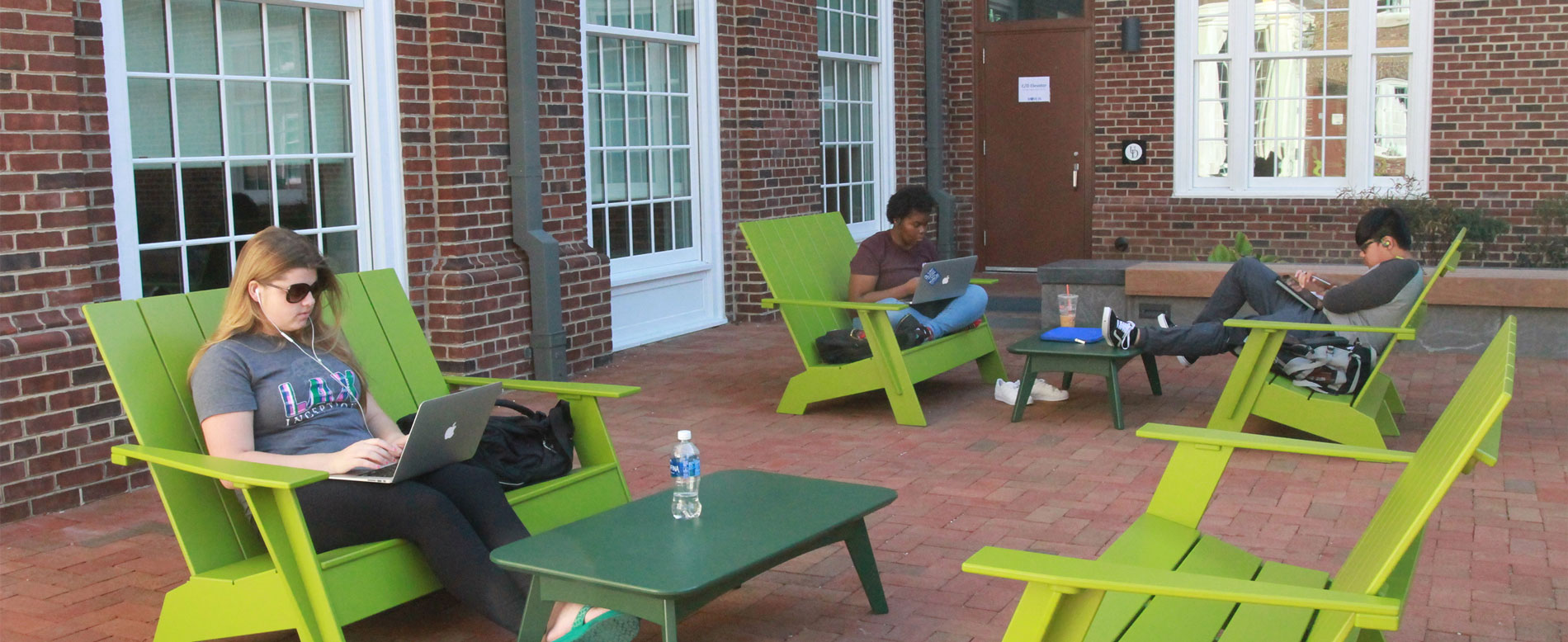 Students working in outdoor space with bright green Adirondack chairs