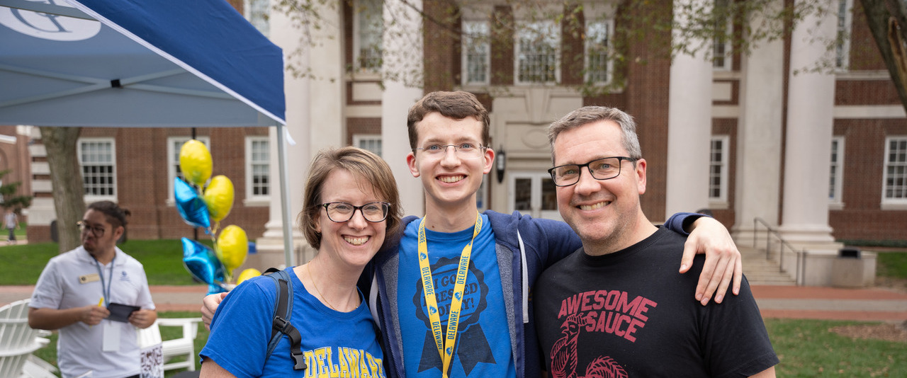 A family of three smiles for a photo at the 2023 Parents and Family Weekend Welcome Reception