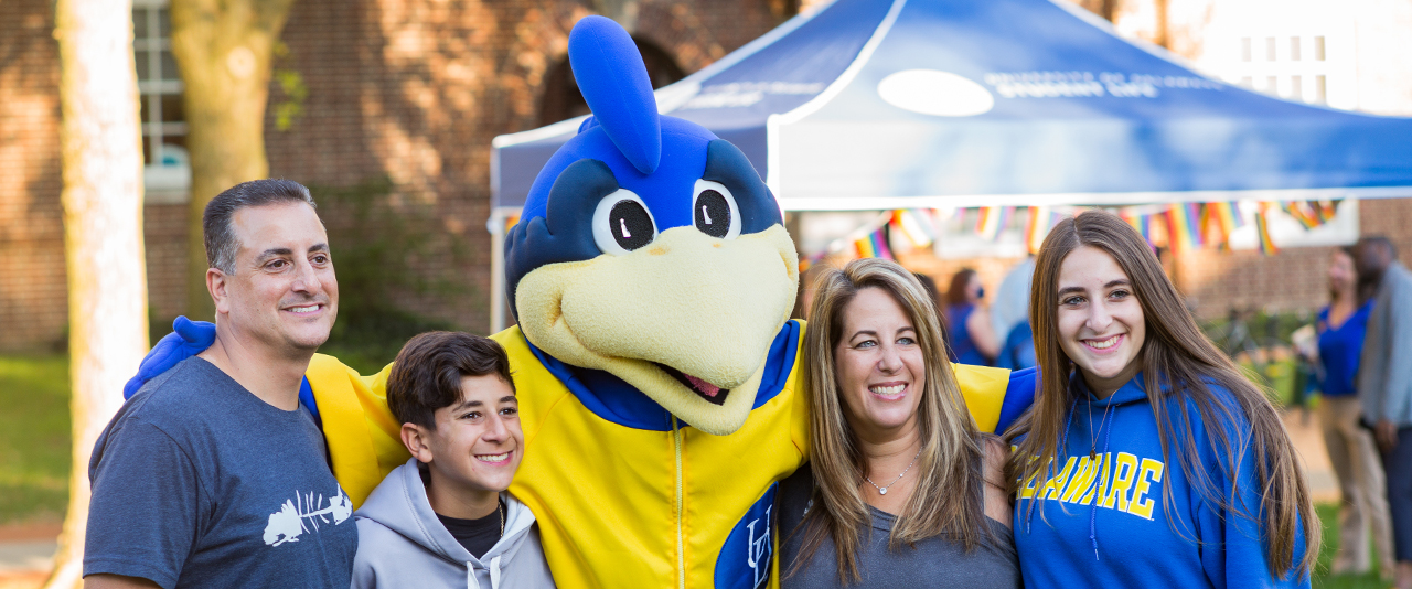 Family poses with YoUDee during Parents and Family Weekend