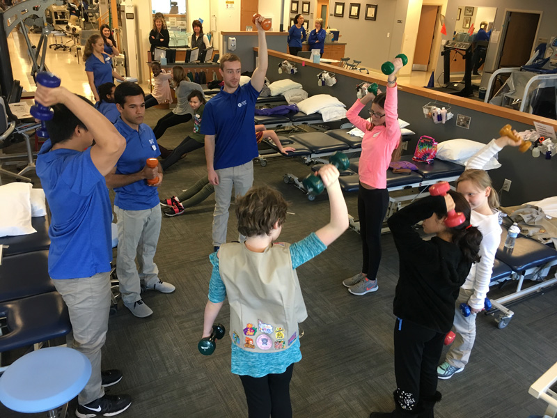 From left to right: Physical therapy graduate students Naoaki Ito, Corey Henley and Kyle Wyss show Girl Scouts a strength exercise.