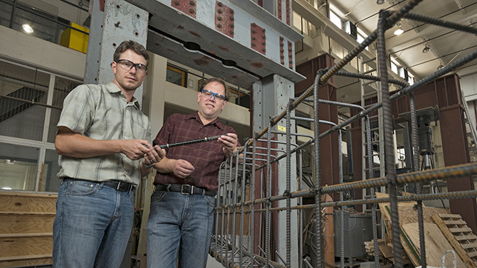 Associate Professors Erik Thostenson (Mechanical Engineering - red shirt) and Thomas Schumacher (Civil & Environmental Engineering - green shirt) are jointly developing a structural health monitoring system using carbon nanotube composites. Photographed in the Dupont Hall Structural Laboratory for a UDaily article.