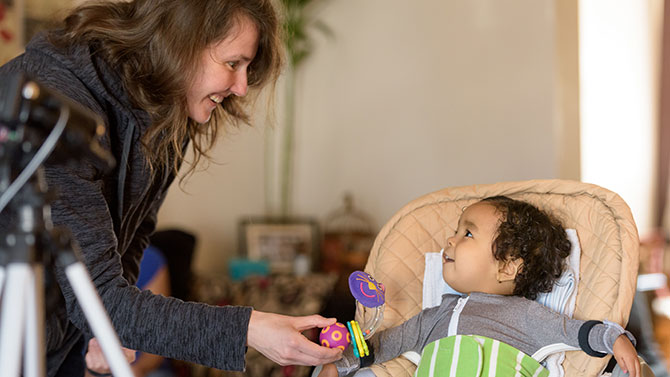 Michele Lobo, assistant professor of physical therapy, and Iryna Babik, a post-doctoral researcher, work with an infant patient wearing a Playskin Lift assistive garment during an exoskeletal garment study / physical therapy session in the patient's home. The PlaySking Lift is an exoskeletal support garment that can be configured to provide varying degrees of assistance and support to a young child's upper body and extremities.  - (Evan Krape / University of Delaware)