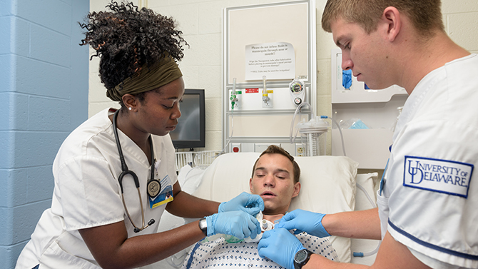 CHS-Nursing-SimUTrach_Training-091316 Undergraduate nursing students Cory Haaf, Jennifer Shellenberger, and Jerelene Thorpe perform various simulated tracheostomy related tasks on "patient" Robert Tilley who's wearing a SimUTrach: a high-fidelity tracheostomy overlay. The SimUTrach device was developed as a senior class project in 2014 by UD students and brought to market by SimUCare, a company based out of the University of Delaware. - (Evan Krape / University of Delaware)