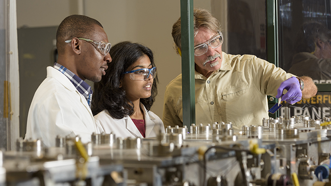 Steve Hegedus, senior scientist in energy conversion, with students Ugochukwu Nsofor and Gowri Sriramagiri working on a project financed by the Department of Energy's (DOE) "SunShot Initiative." Overseen by the DOE's Solar Energy Technologies Office, SunShot funds cooperative projects which help to reduce the cost of solar power generation to a target of $0.06 per kilowatt-hour ($1 per watt) without additional incentives or subsidies.  - (Evan Krape / University of Delaware)