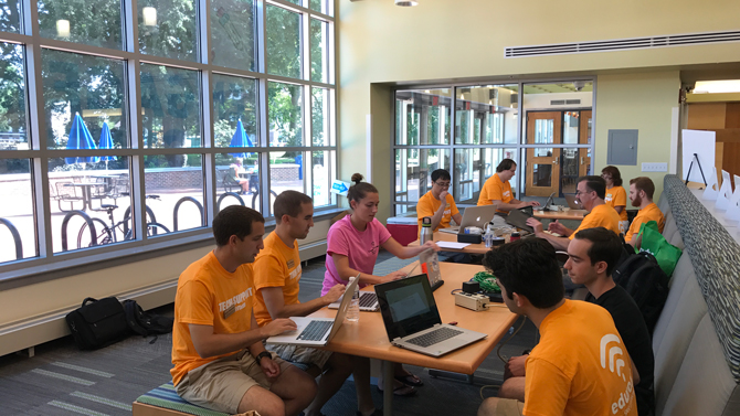 IT Help crew at Harrington Commons, student in pink shirt, window background on Move-in day Saturday, Aug. 26