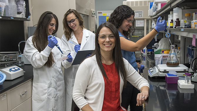Emily Day, received a NIH Grant for her work with nanoparticles along with her doctoral students Rachel Riley (blue shirt/dark hair), Jilian Melamed (really long hair) and Danielle Valcourt (lt brown hair) in her lab at 5 Innovation Way.