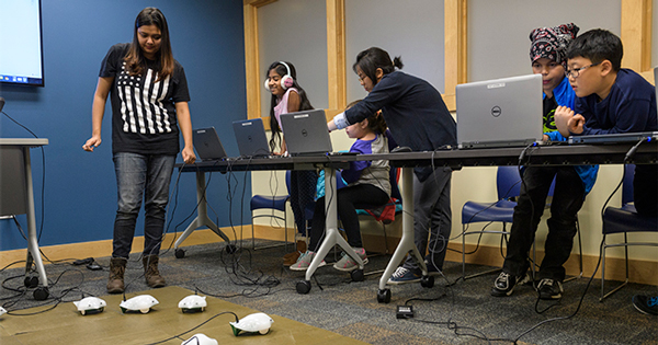 Education doctoral students Soumita Basu (left) and Hui (Mocha) Yang (center) help young coders learn at the Newark Free Library.
