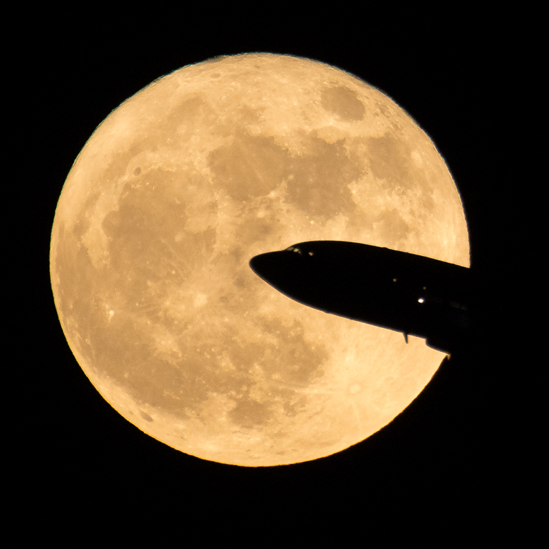 Airplane takes off with supermoon in the background