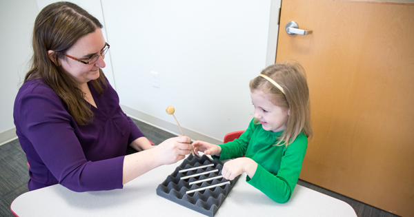 Postdoctoral researcher Maura Curran (left) teaches a child about sound.