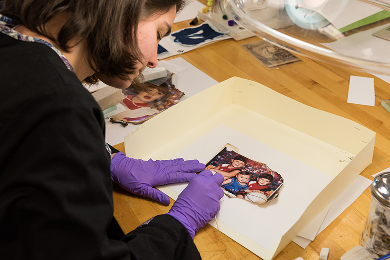 Graduate students in the Winterthur / University of Delaware Program in Art Conservation (WUDPAC) working to stabilize and restore family photos recovered from the aftermath of a tragic Christmas day fire which claimed the lives of 3 children and their grandmother. The photos were brought to the attention of Debbie Hess Norris, Chairperson of the Art Conservation department and photo conservator, by Michael Emmons, a PhD student in the Art Conservation department and friend of the family. All of the time and material costs of the preservation, stabilization, scanning, and digital restoration of the photos is being donated by the University of Delaware and Winterthur to the family.
