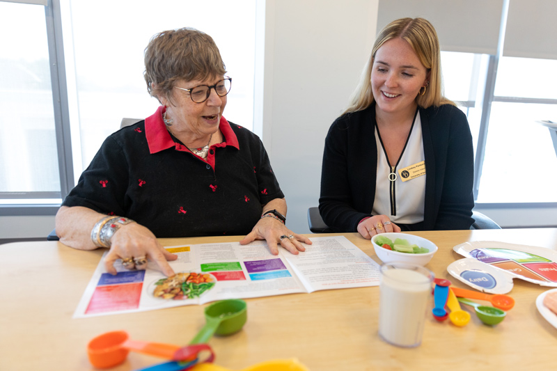 Dietetic intern Lindsey Paniszczyn (right) works with Prevent T2 program participant Susan Riedy on healthy eating strategies as they review CDC curriculum “Eating Well to Prevent T2.”