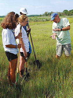 A teacher with students in a marsh for TideCamp