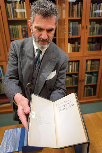 Mark Samuels Lasner holding open a book from his collection