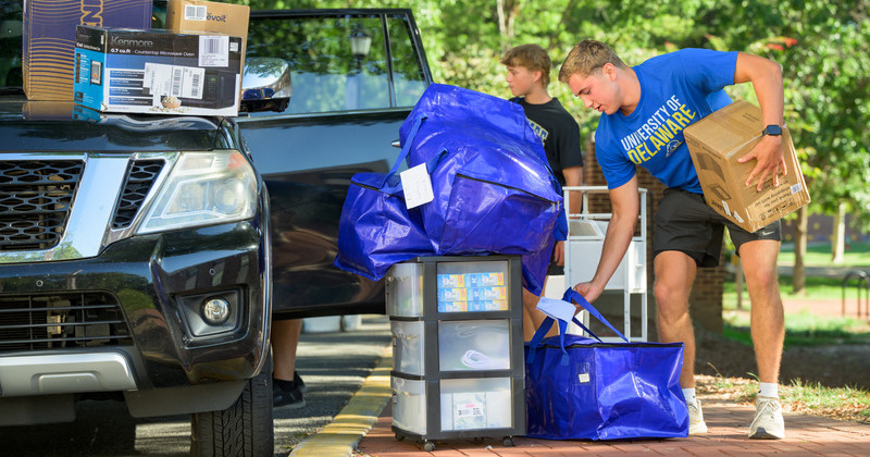 Students carrying things in from a car
