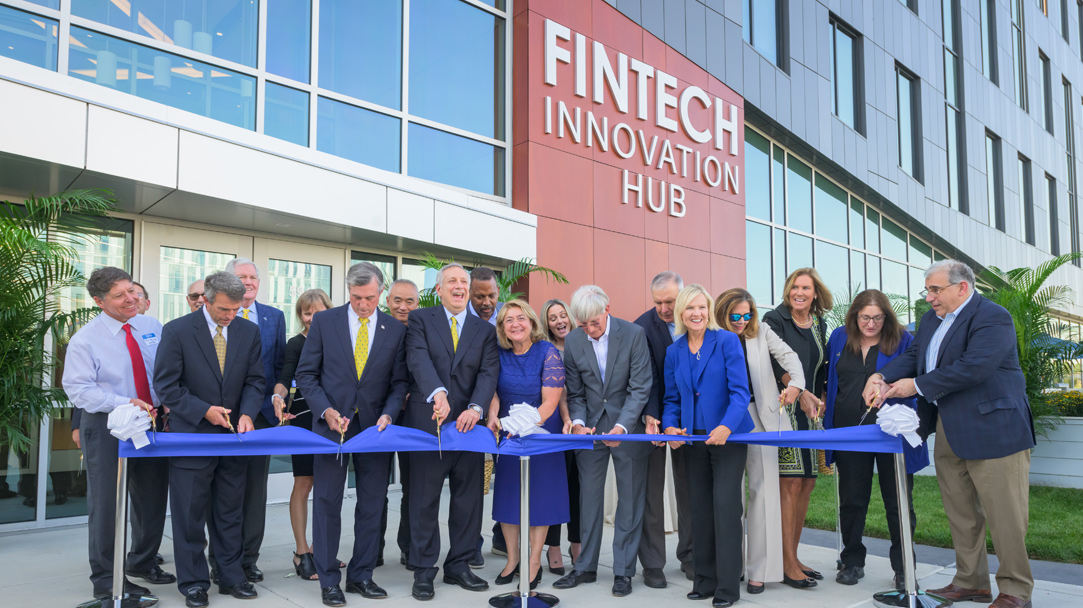 UD President, Dennis Assanis, Delaware Governor John Carney, and other local dignitaries cut a blue ribbon to commemorate the opening of UD's Fintech Innovation Building.