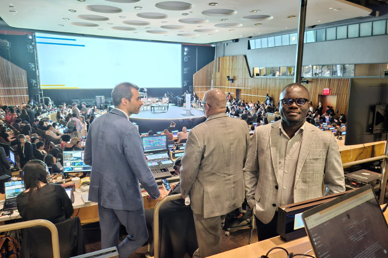 UN Summit of the Future Individuals stand around mingling a large event space with lighting, computers and a large stage in the background