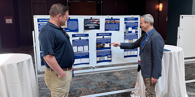 Scott Abbott and NCHE Conference attendee stand in front of his poster presentation