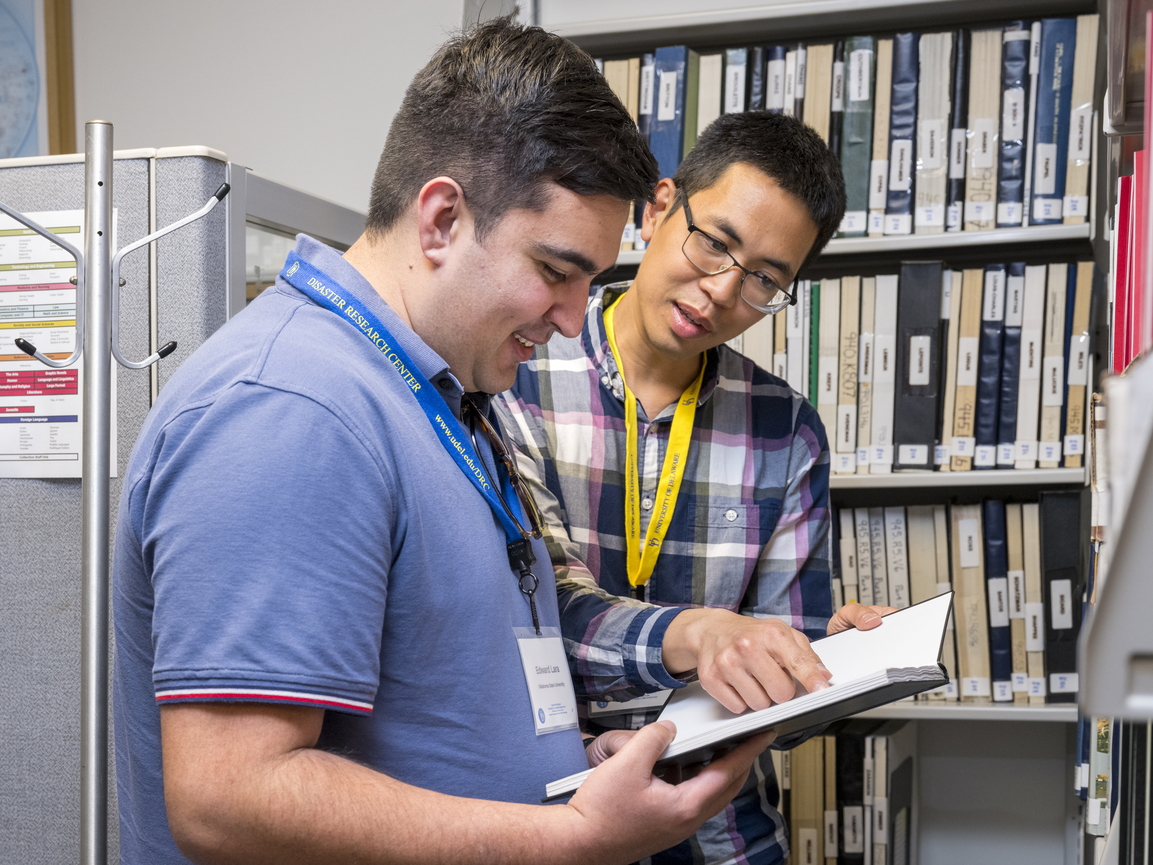 Two individuals review the research collection at the Disaster Research Center