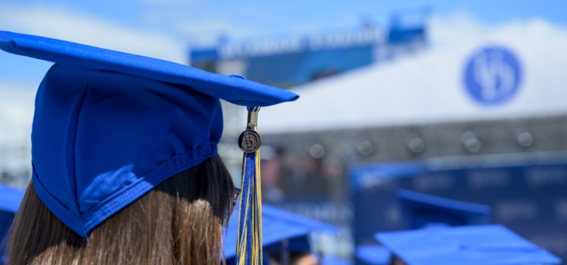 Associate of Arts in Community and Non-profit Leadership A person wearing a blue graduation cap and tassle