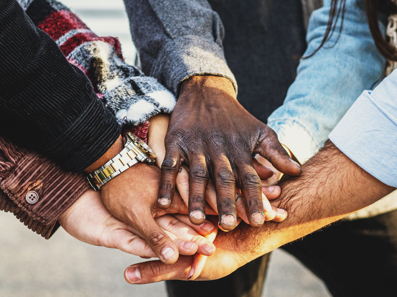 Closeup photo of a stack of hands gathered togethered as a sign of togetherness and teamwork