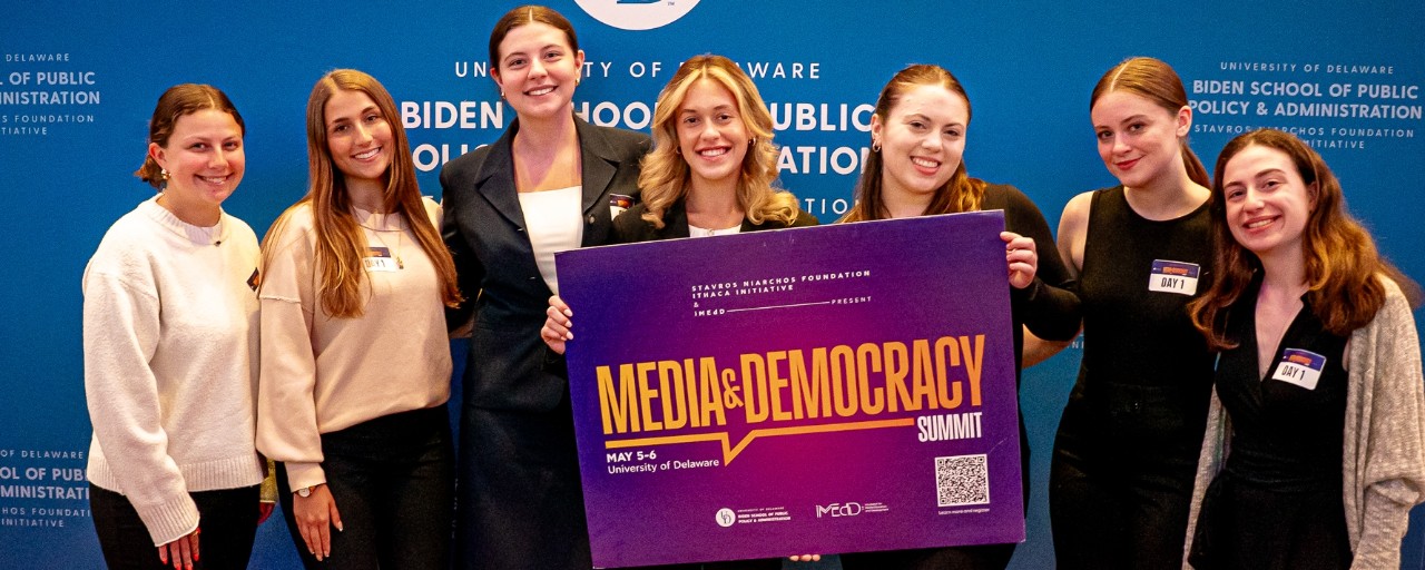 SNF Ithaca x iMedD Media and Democracy Summit A group of adults standing while holding a sign