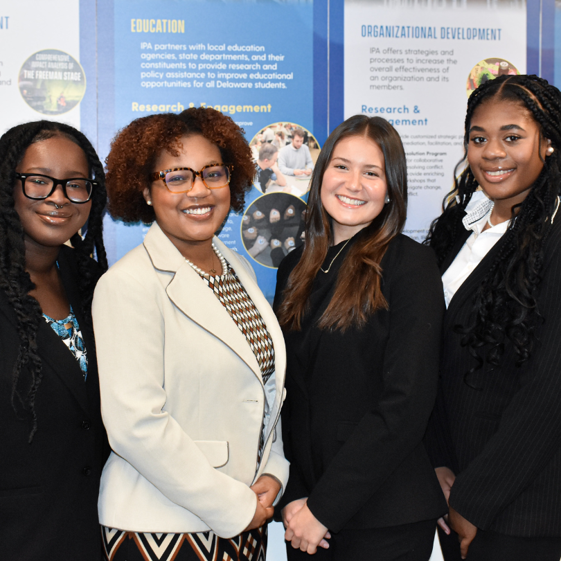 Four students smiling wearing professional dress