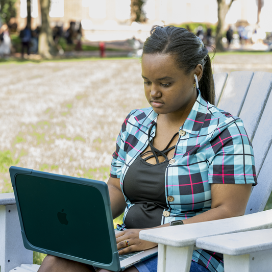 Person sitting outside looking at a laptop
