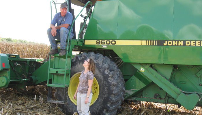James Adkins and Amy Shober in a field with a green tractor