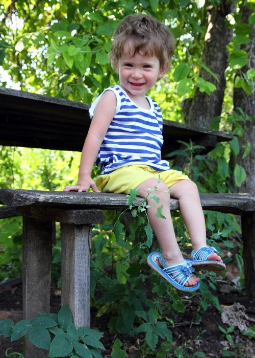 Small child on a bench in a natural area.