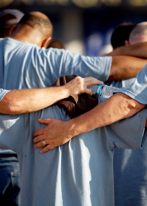 A group with arms around each other in prayer.