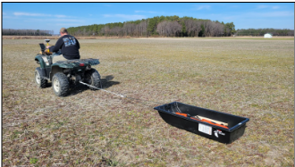 Figure 3: An EM38 being pulled in a plastic sled to minimize contact with metal. A GPS unit is mounted to the 4-wheeler to georeference the ECa measurements (photo: Jarrod Miller).