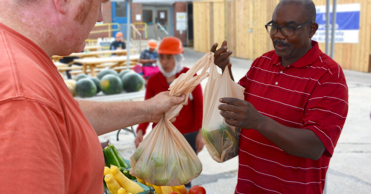 Man purchases fresh vegetables and fruit from a worksite farmer's market.