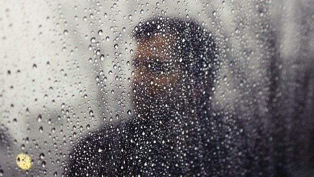 A man looking through a rainy window. 