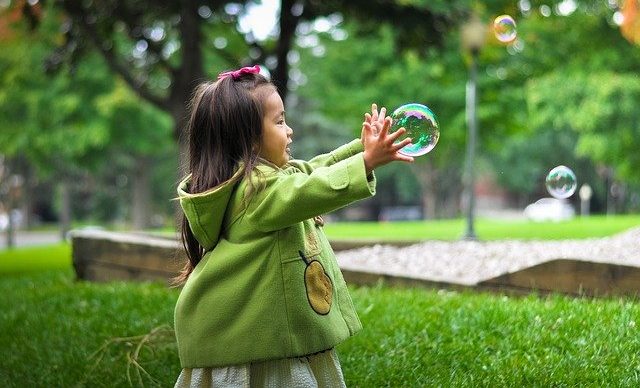 A little girl plays with bubbles.