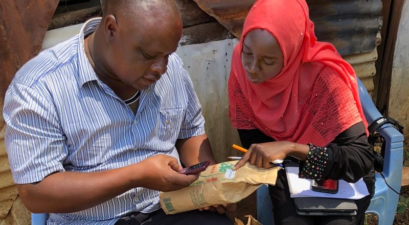  University of Delaware alumnus Mariam Gharib (right) helps a Kenyan farmer verify the corn seed’s authenticity by submitting the certification code listed on the seed packet to the manufacturer via a text from his cell phone. 