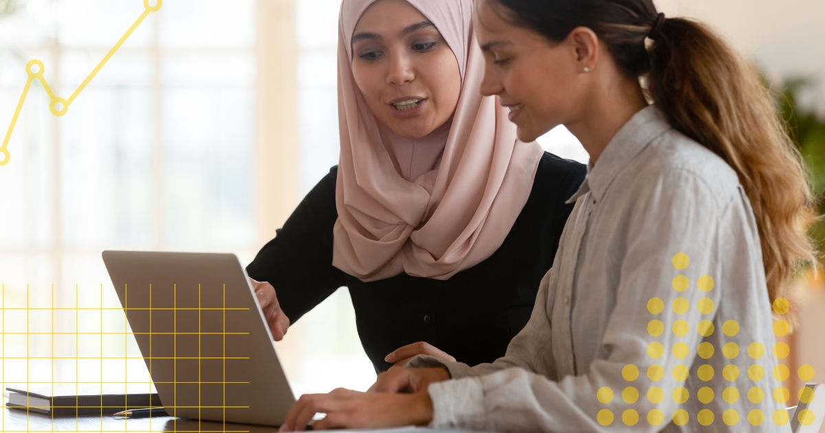 Two women working at a computer on a statistics project.