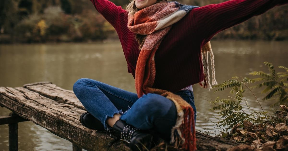 A woman sitting on a pier, practicing mindfulness in winter.