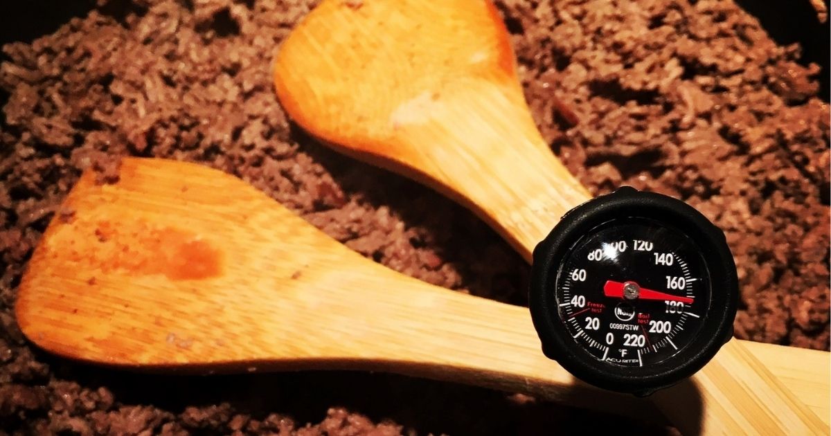 Ground beef cooking in a pan with a meat thermometer