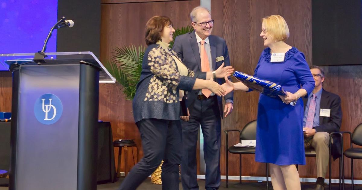 Kathleen Splane receives her award and shakes hands with Dr. Michele Rodgers on stage.