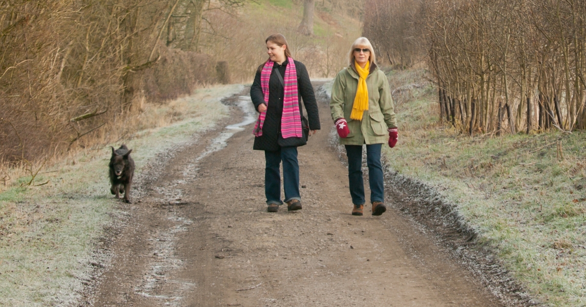 Two women and a dog walking a trail in winter