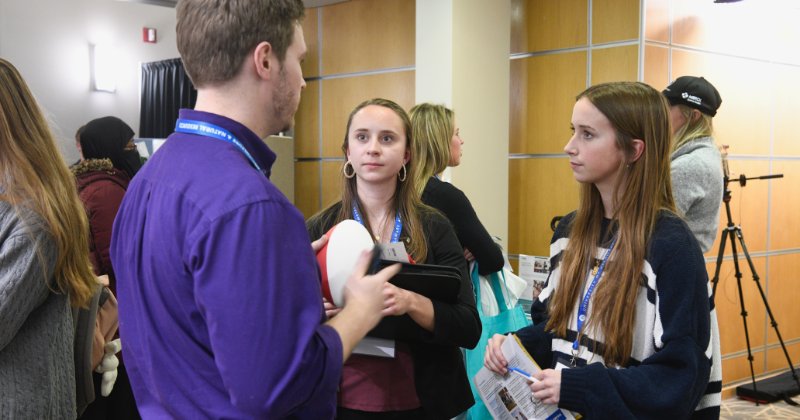 Maci Carter (right) and Brielle Carter (left) speak with UD Class of 2021 alumnus Cole Macron, who represented Willard Agri-Service at the event.