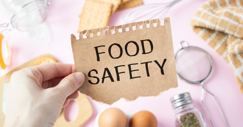 Illustration of of hand holding a perforated paper that reads "food safety"