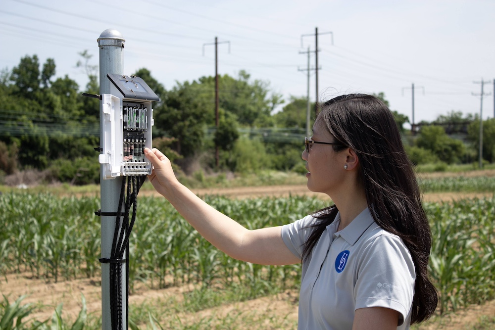 Qi Mu checking a soil sensor on a sunny day.